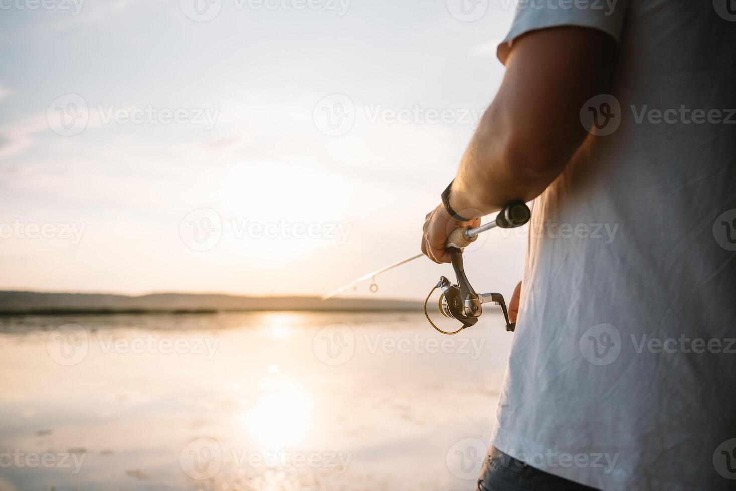 The fisherman's hands, holds the spinning rod, rotates the coil handle. Hobby and activity. photo