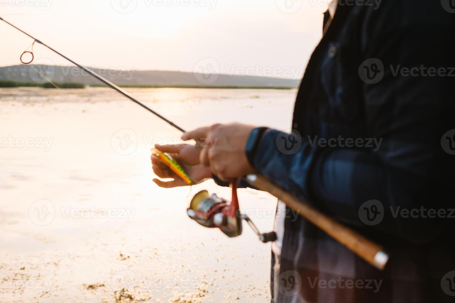 The fisherman's hands, holds the spinning rod, rotates the coil handle. Hobby and activity. photo