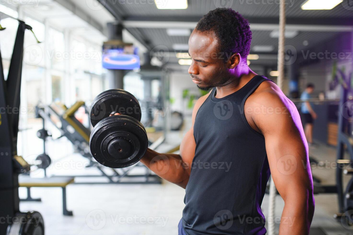 Young man strengthening biceps with dumbbell in gym photo