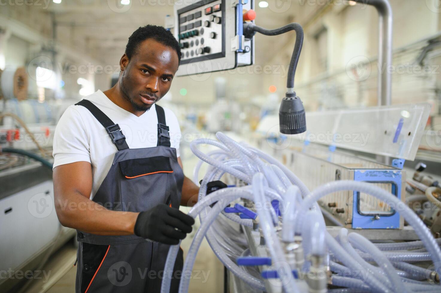 Portrait of African American male engineer in uniform and standing in industrial factory photo