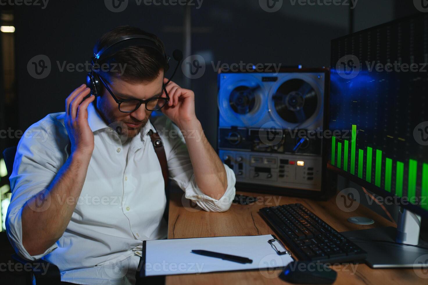 A male spy listens and records conversations on a reel-to-reel tape recorder photo