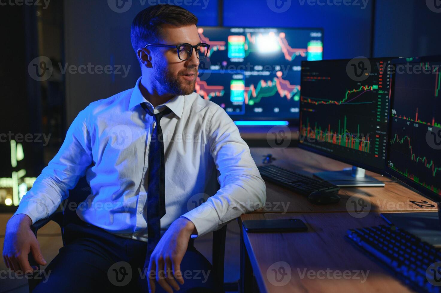 Side view of crypto broker sitting at office table, analyzing market, looking at screen photo