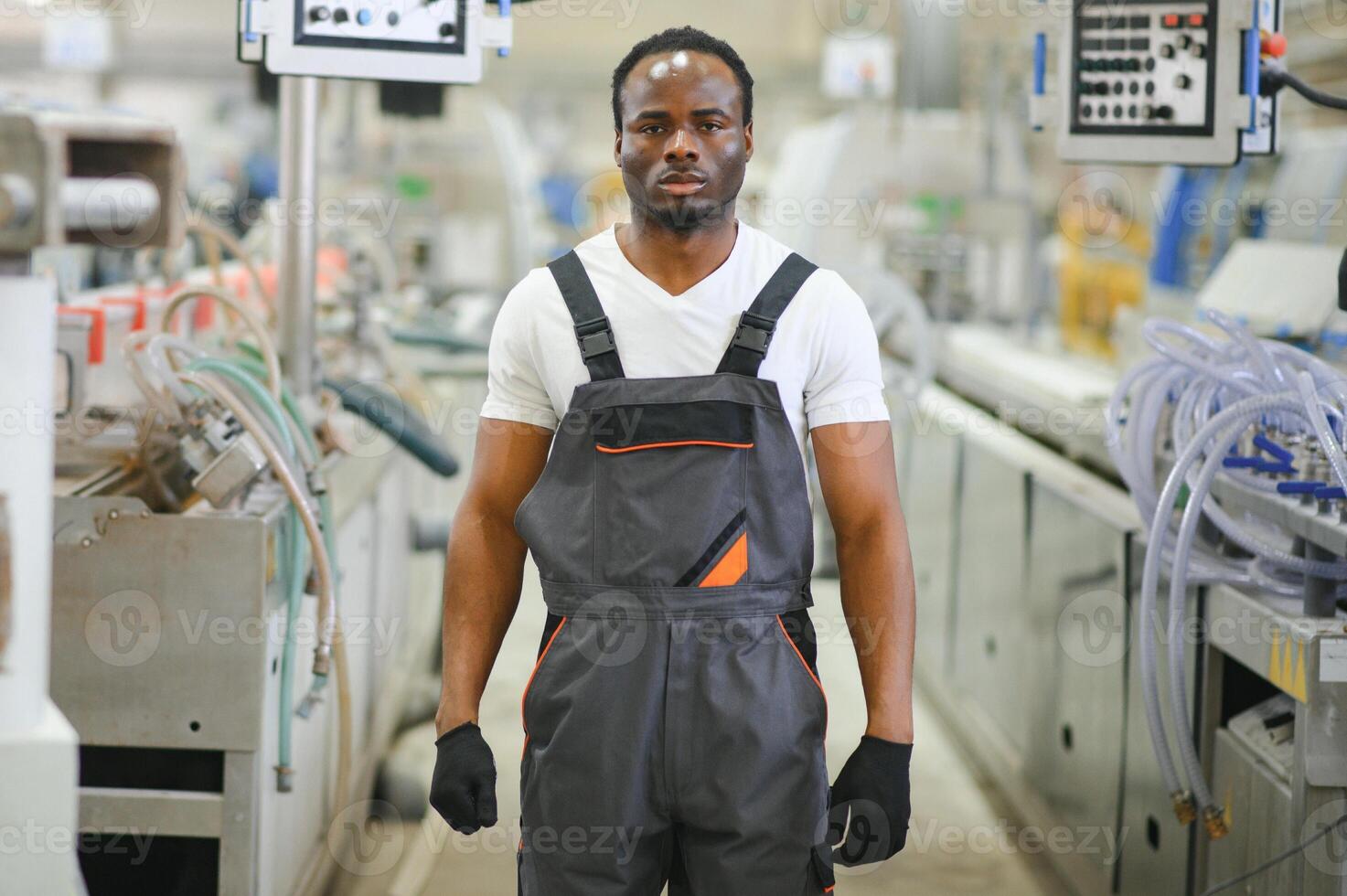 Portrait of African American male engineer in uniform and standing in industrial factory photo