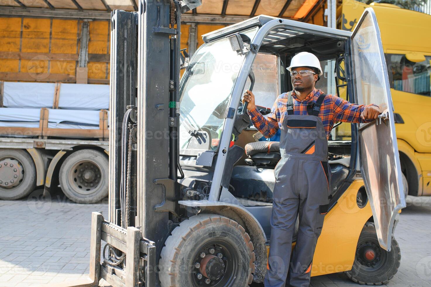 Portrait of a happy African American male worker driving forklift at workplace photo