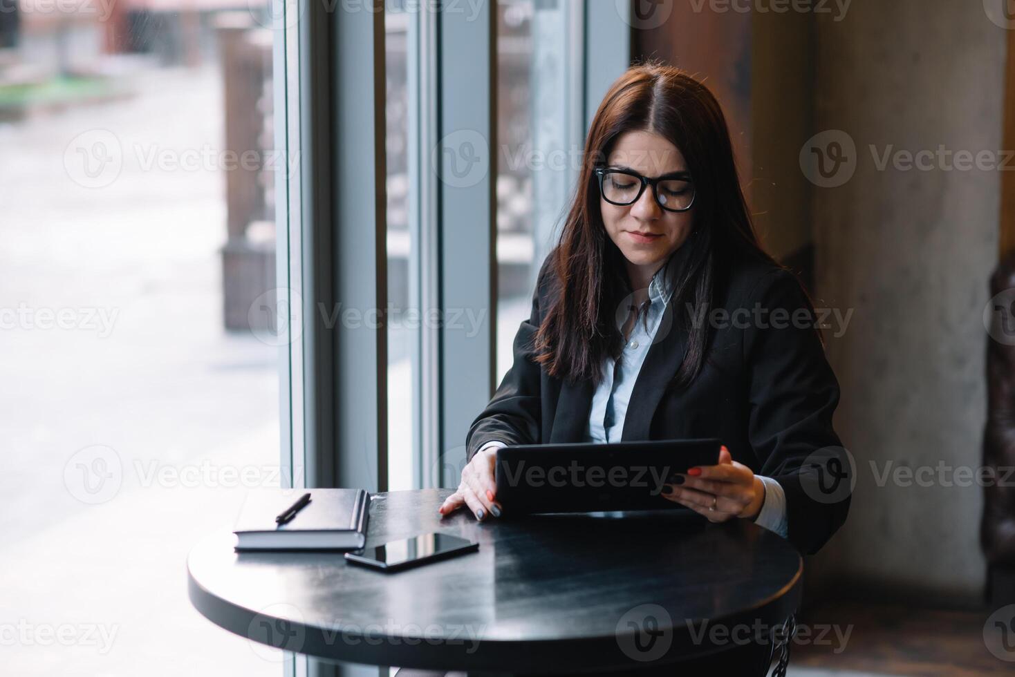 Happy young businesswoman using tablet computer in a cafe. Selective focus photo