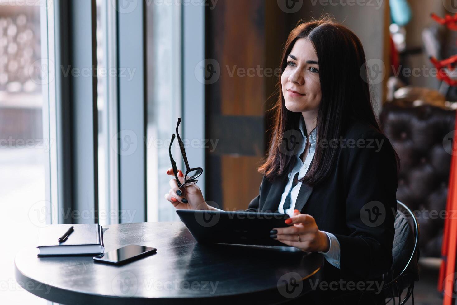 contento joven mujer de negocios utilizando tableta computadora en un cafetería. selectivo atención foto