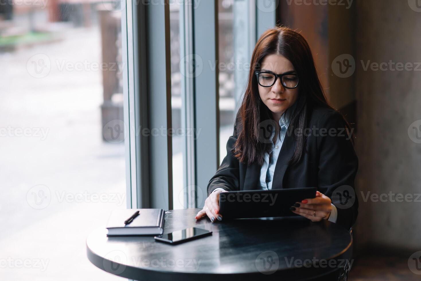 Happy young businesswoman using tablet computer in a cafe. Selective focus photo