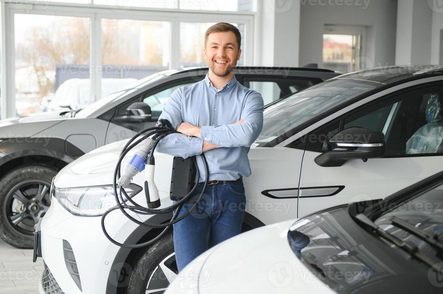 A happy man chooses a new electric car at a car dealership. The concept of buying an ecological car photo