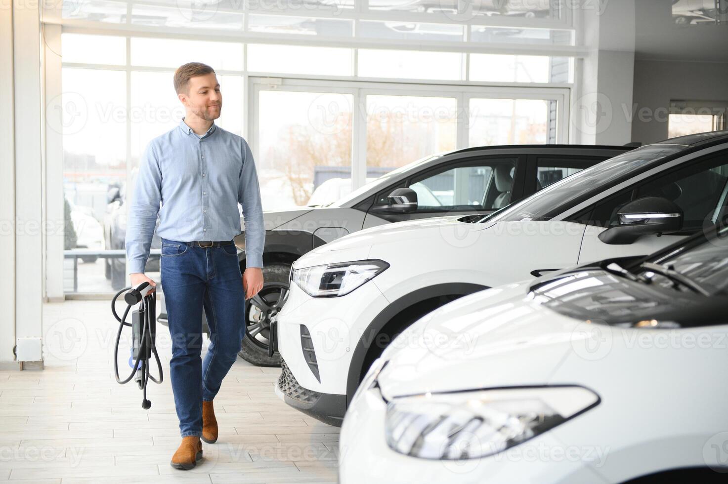 A happy man chooses a new electric car at a car dealership. The concept of buying an ecological car photo