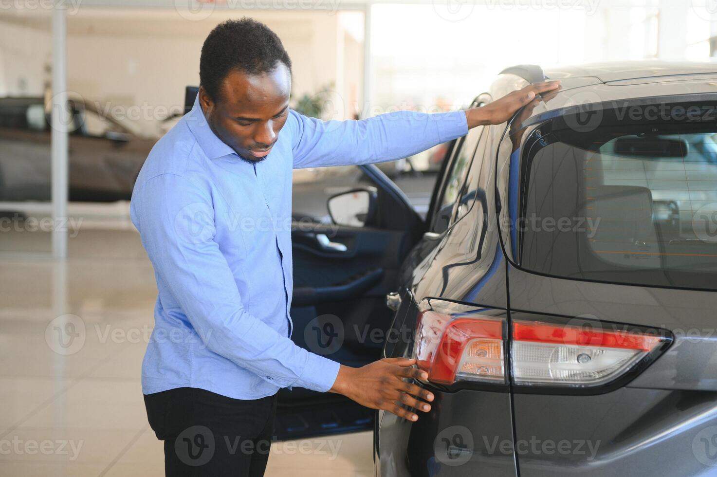 young africanamerican man came to see automobiles in dealership or cars showroom photo