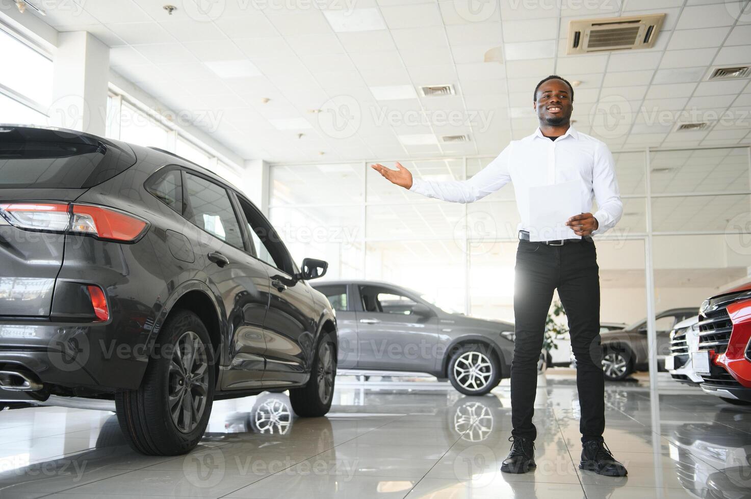 carros concesión concepto. auto vendedor afro hombre en pie en automóvil centrar foto