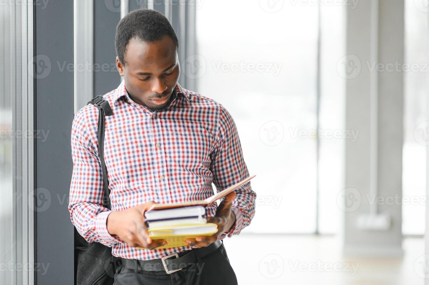 handsome college boy holding books on campus photo
