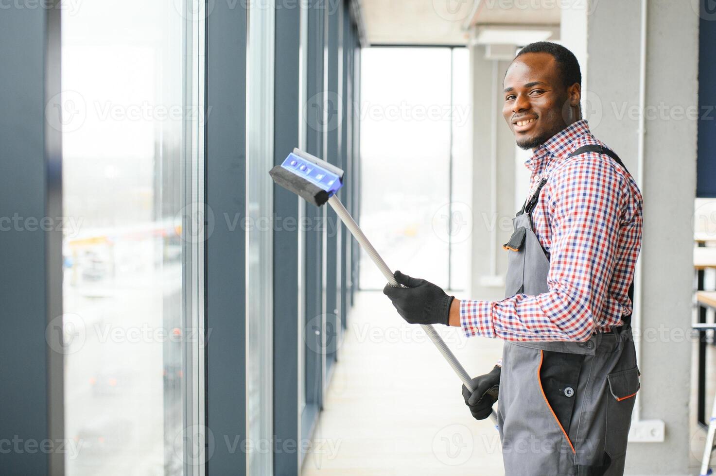 Happy Male Worker Cleaning Glass With Squeegee And Spray Bottle photo