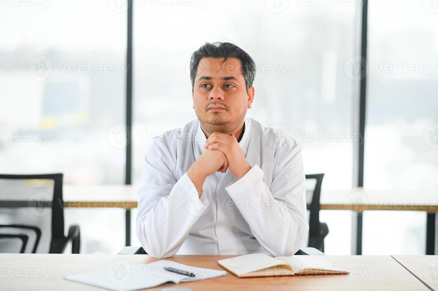 Tired Indian doctor working in medical office photo