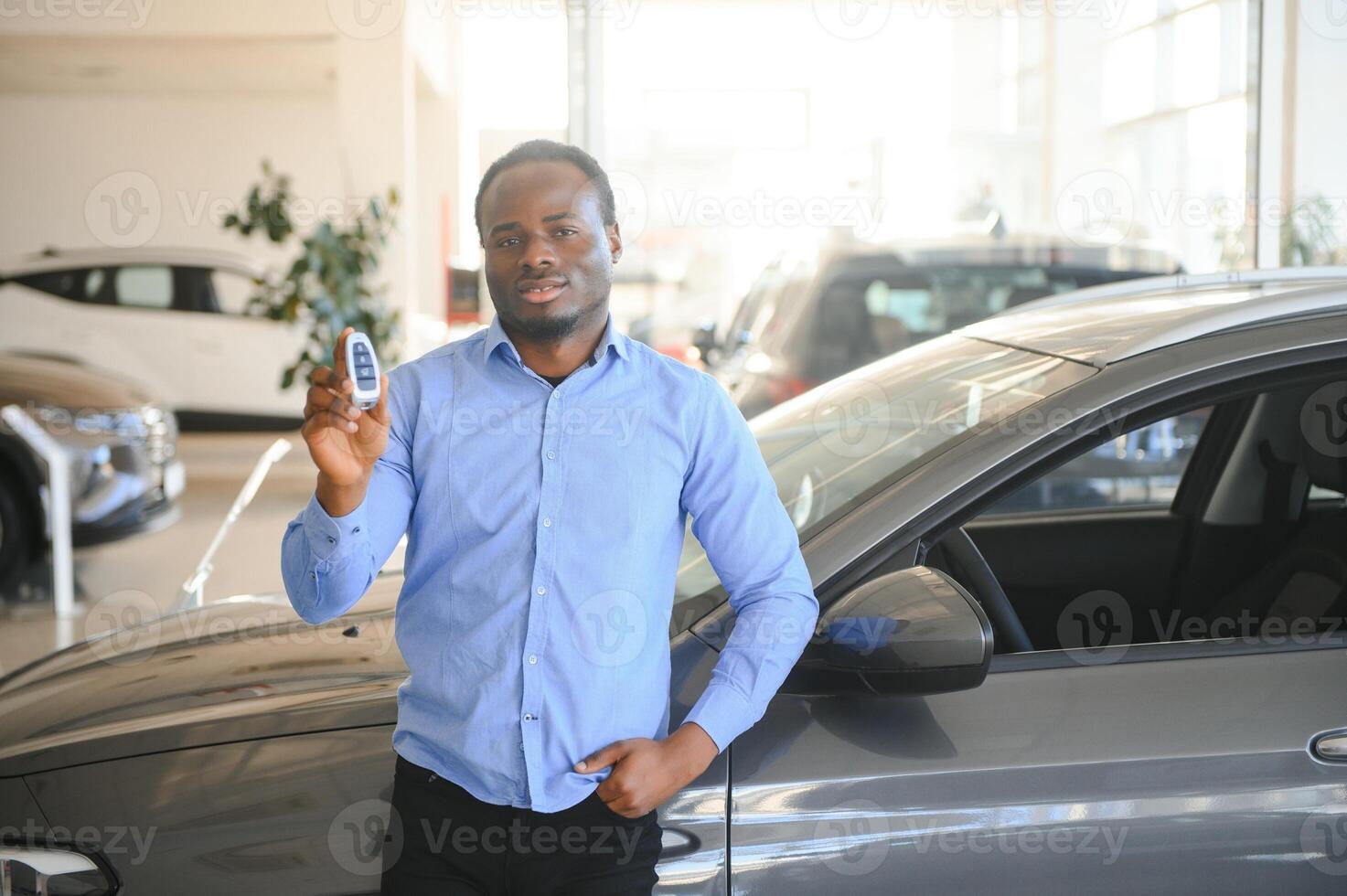 Happy smiling man holding car keys offering new car on background photo