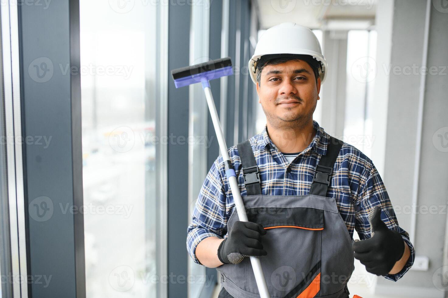 Male janitor cleaning window in office photo