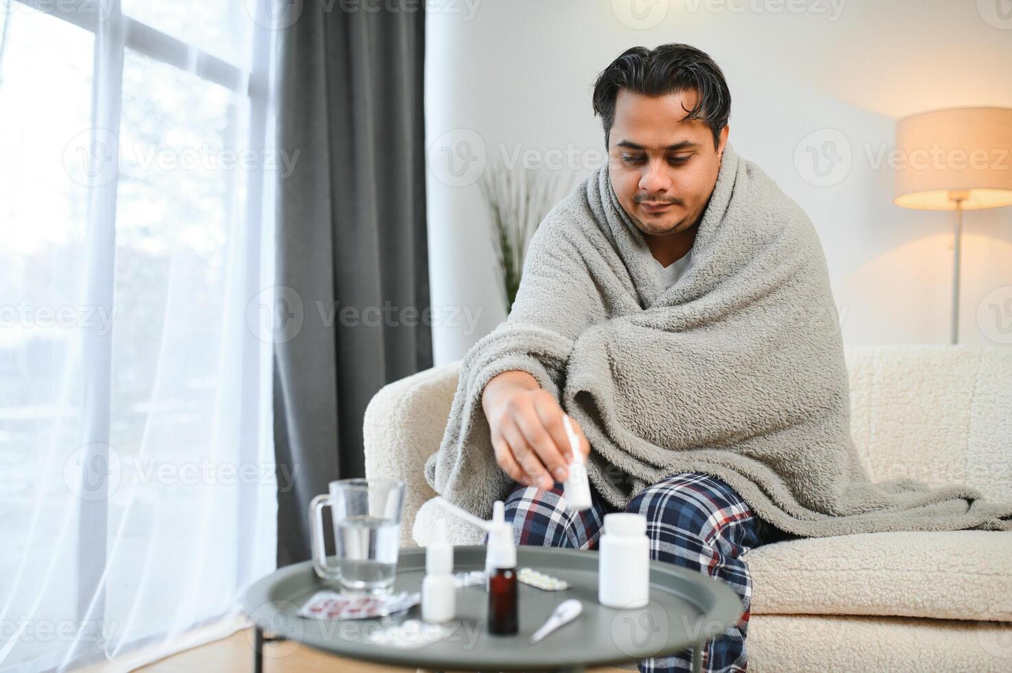 Sick Indian man in plaid sit alone shivering from cold. Unhealthy Arabian guy sit on chair feeling discomfort try to warming up photo