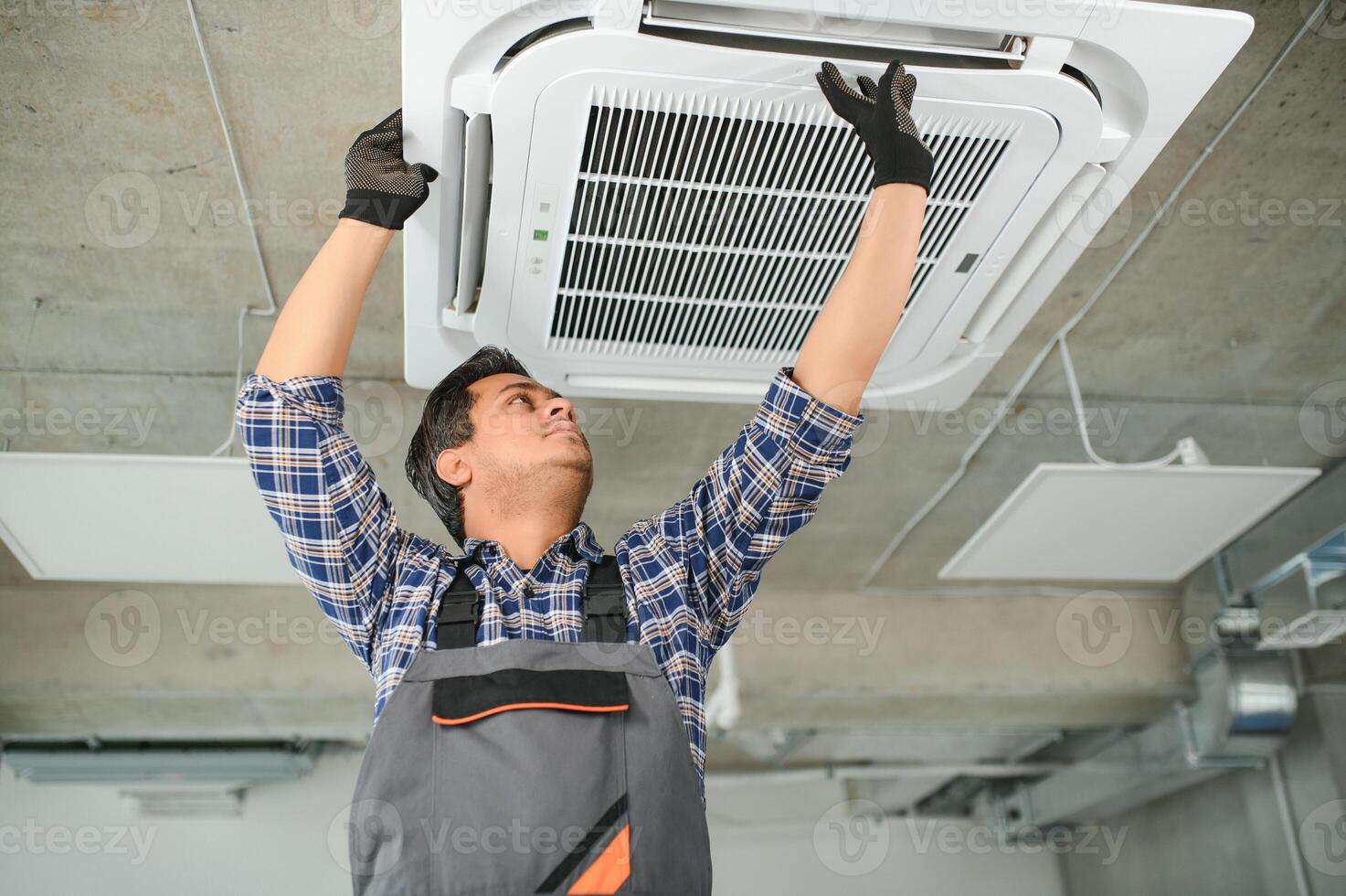 Portrait of young male indian technician repairing air conditioner. Air conditioner repairs. photo