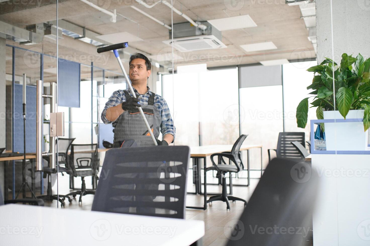 Male professional cleaning service worker cleans the windows and shop windows of a store with special equipment photo