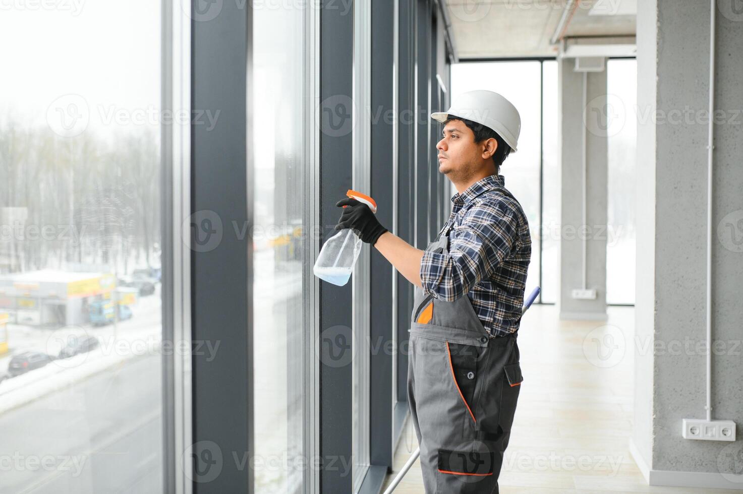 Male janitor cleaning window in office photo