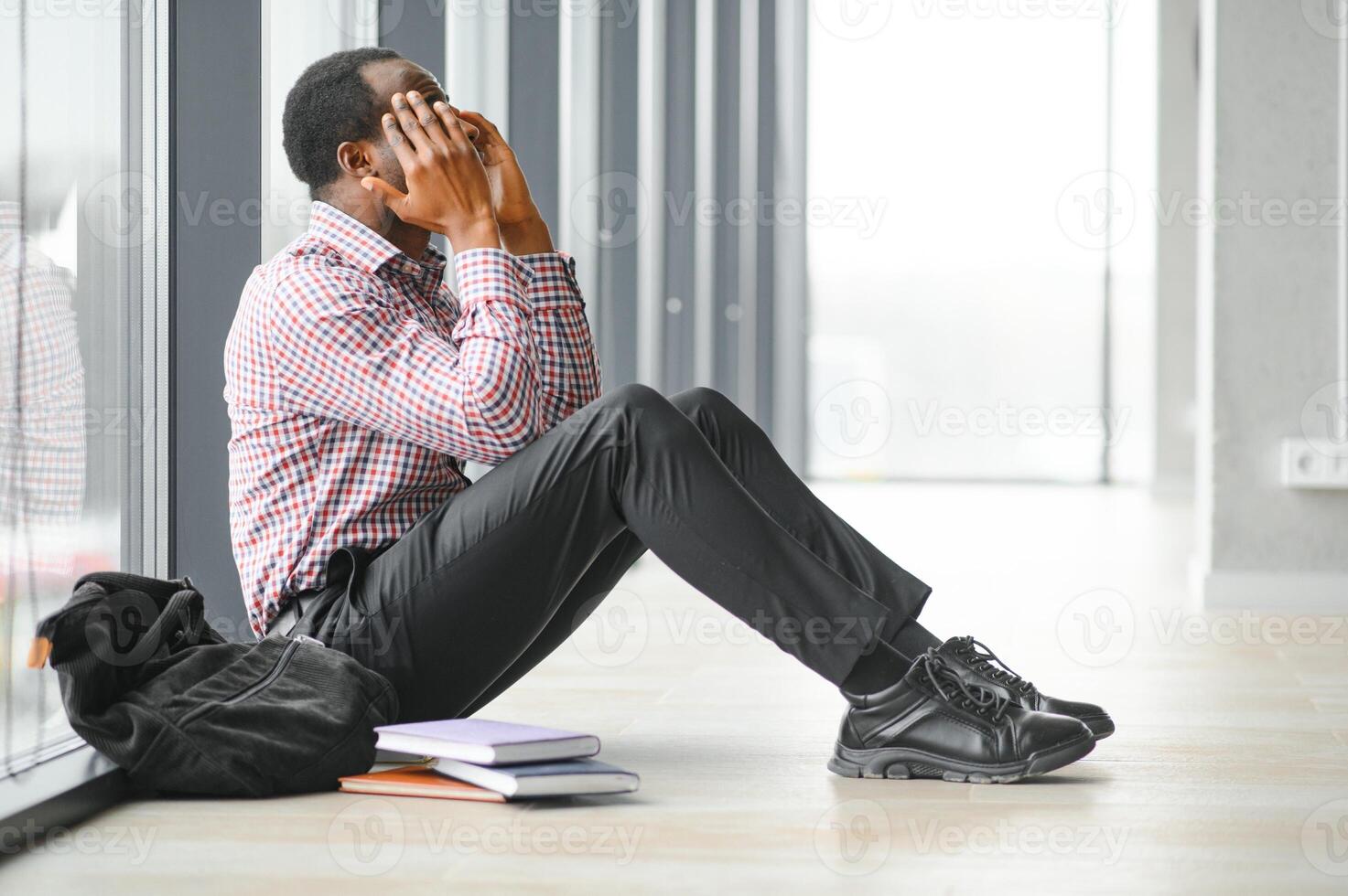 School bullying. Afro american male teenager desperate seated in school hallway photo