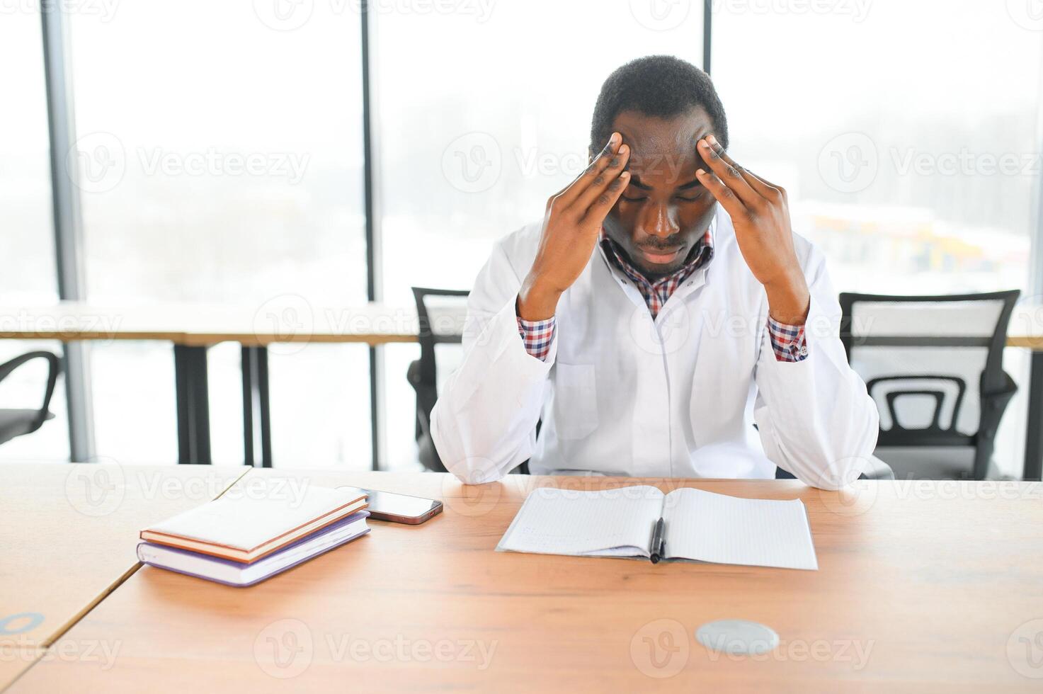 african doctor sitting tired at the table in the hospital photo