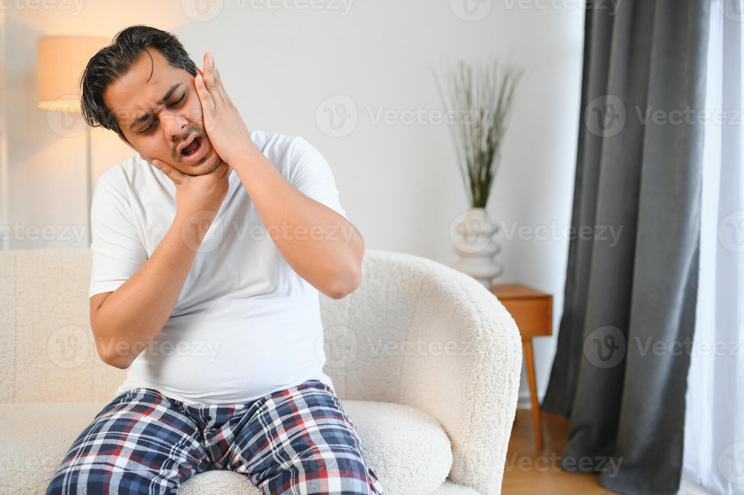 Toothache concept. Sad unhealthy indian or arabian guy touching cheek with hand with painful expression photo