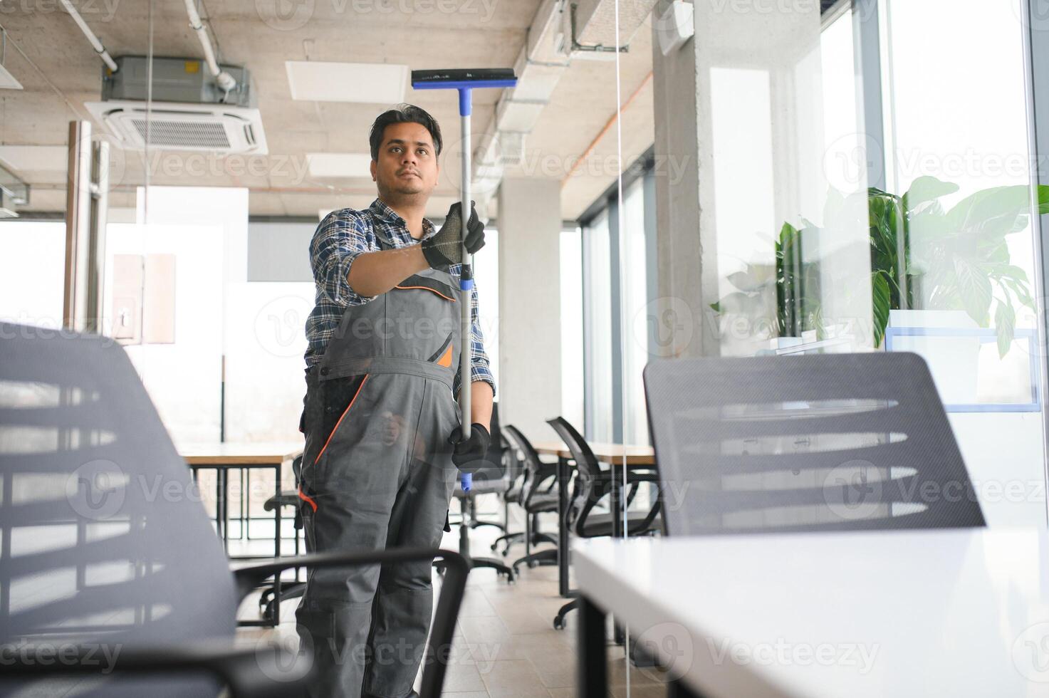 Male professional cleaning service worker in overalls cleans the windows and shop windows photo