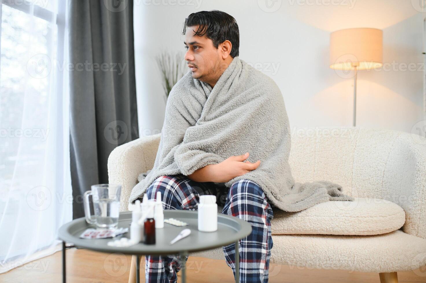 Sick young hindu man feeling bad in the morning, sitting on bed photo