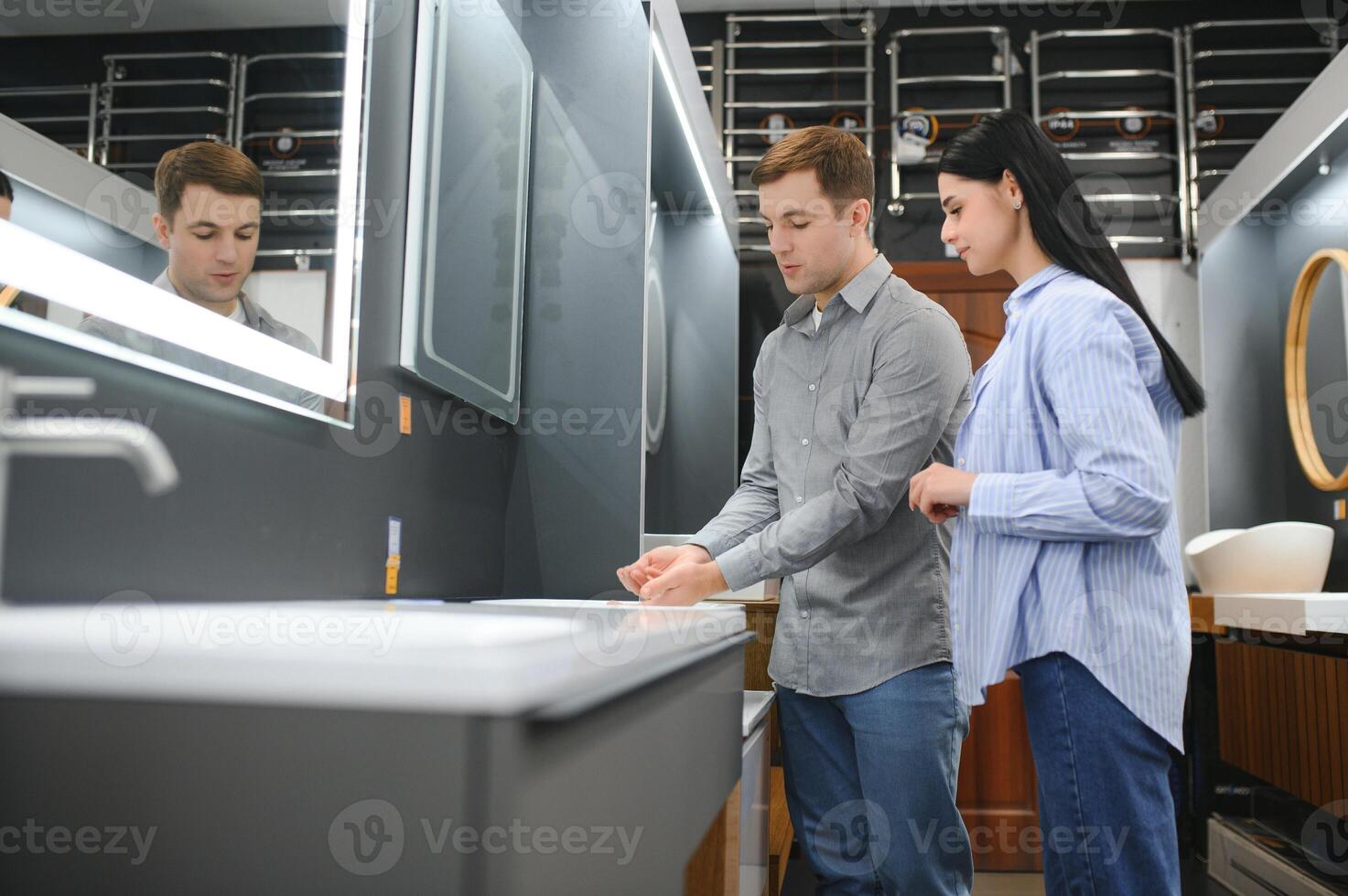 Young couple choosing new bathroom furniture at the plumbing shop with lots of sanitary goods photo