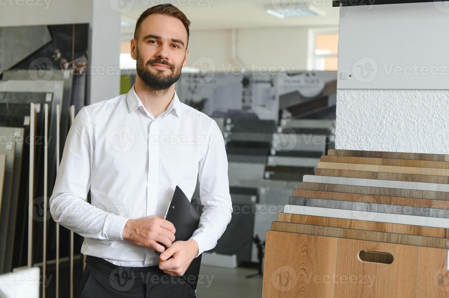 Portrait of a ceramic tile seller. The seller stands against the background of a large assortment of tiles photo