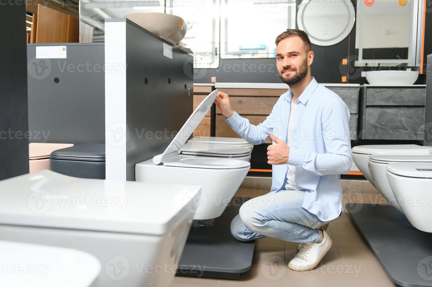 in a plumbing store, a man chooses a new toilet bowl photo