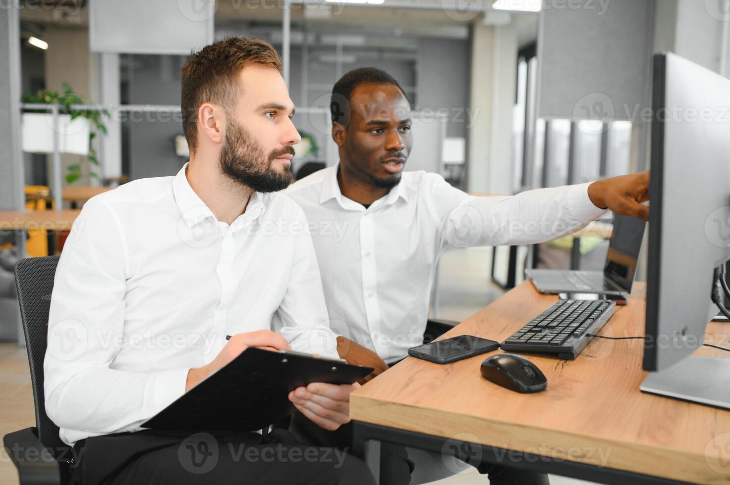 Two successful trader sitting in office, checking cryptocurrency information data on finance market graph, pointing on monitor photo