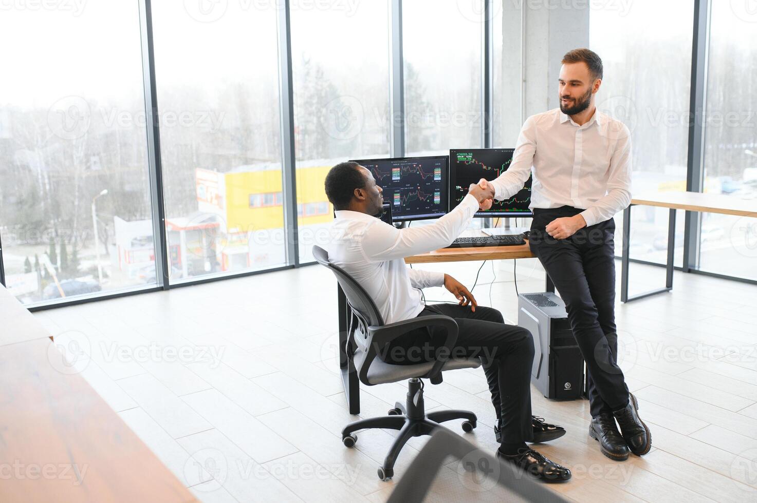 Two men colleagues traders sitting at desk at office monitoring stock market photo