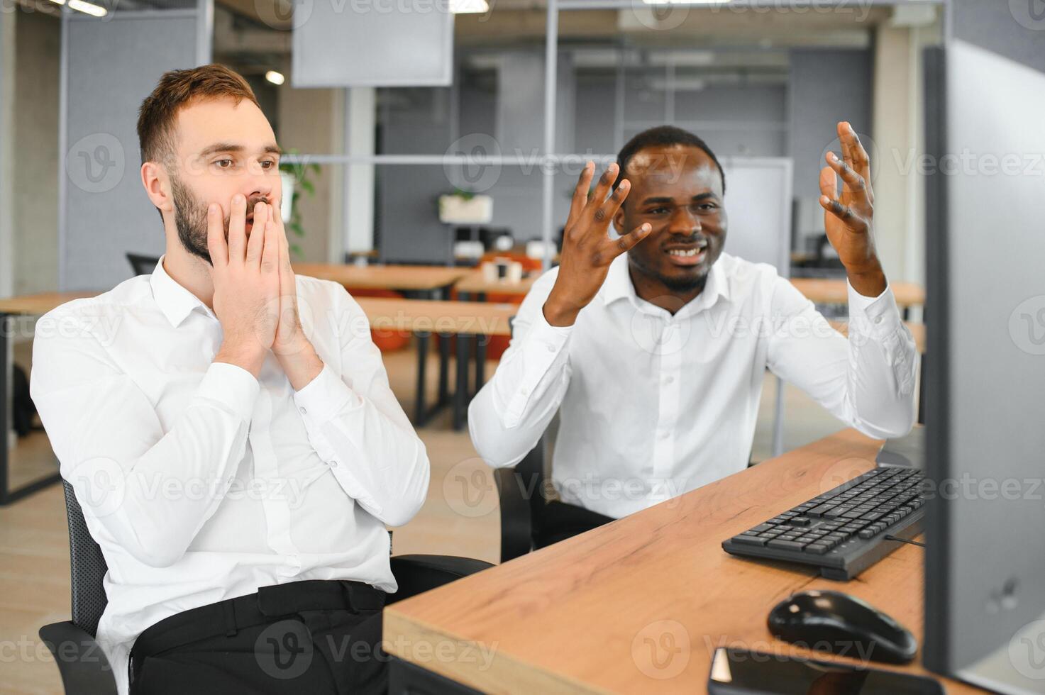 Two diverse colleagues traders talking to each other, sitting in the office in front of multiple computer screens. Stock trading, people, business concept photo