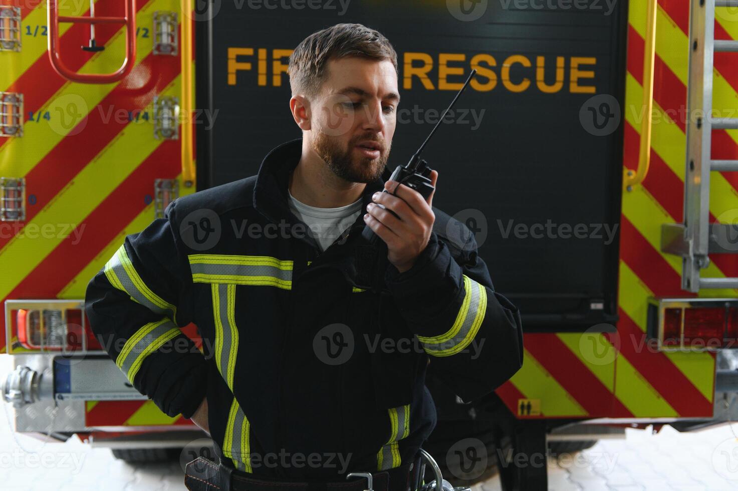 bombero en protector uniforme en pie cerca fuego motor en estación foto