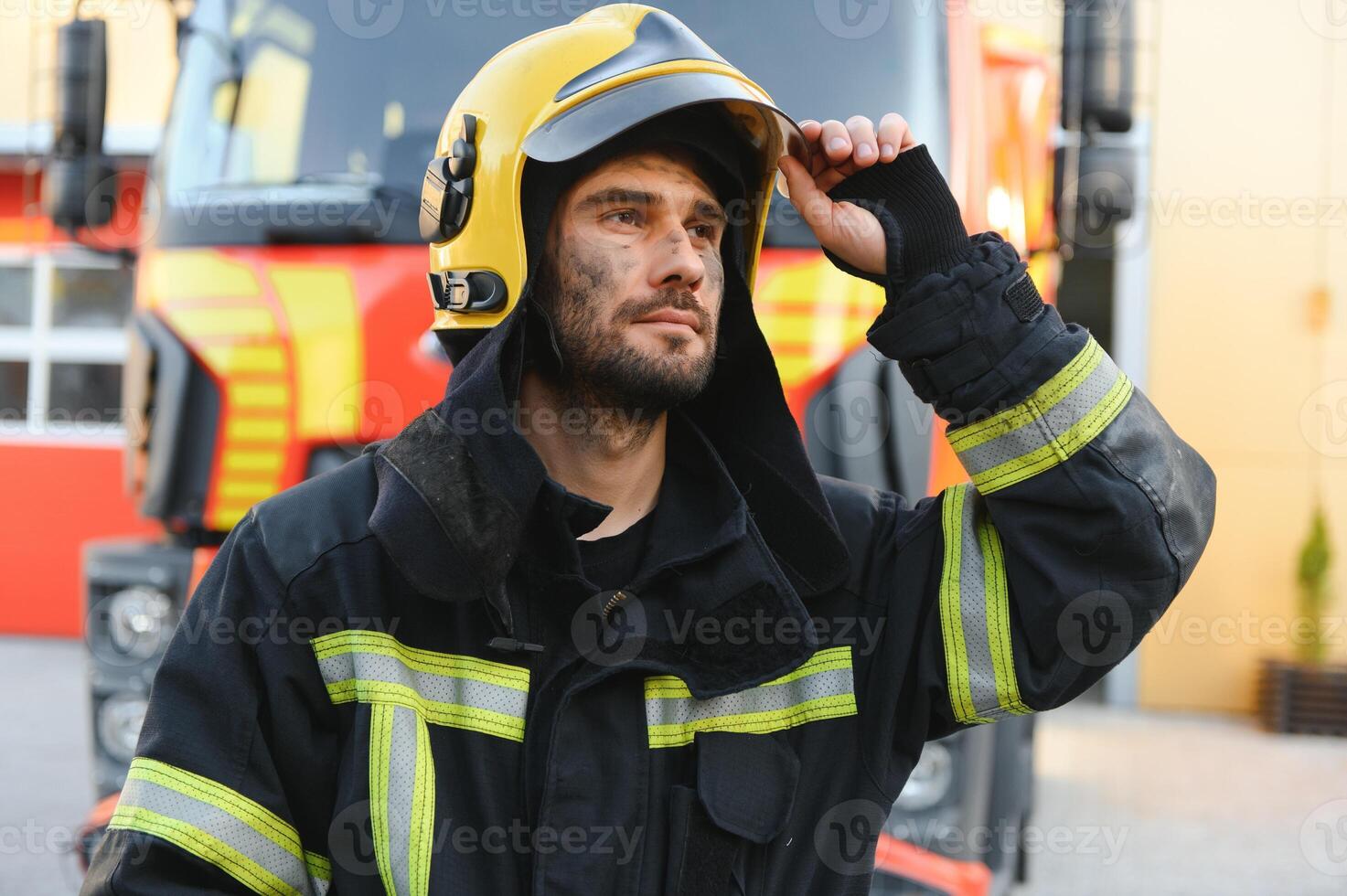 fireman in protective uniform standing near fire engine on station photo