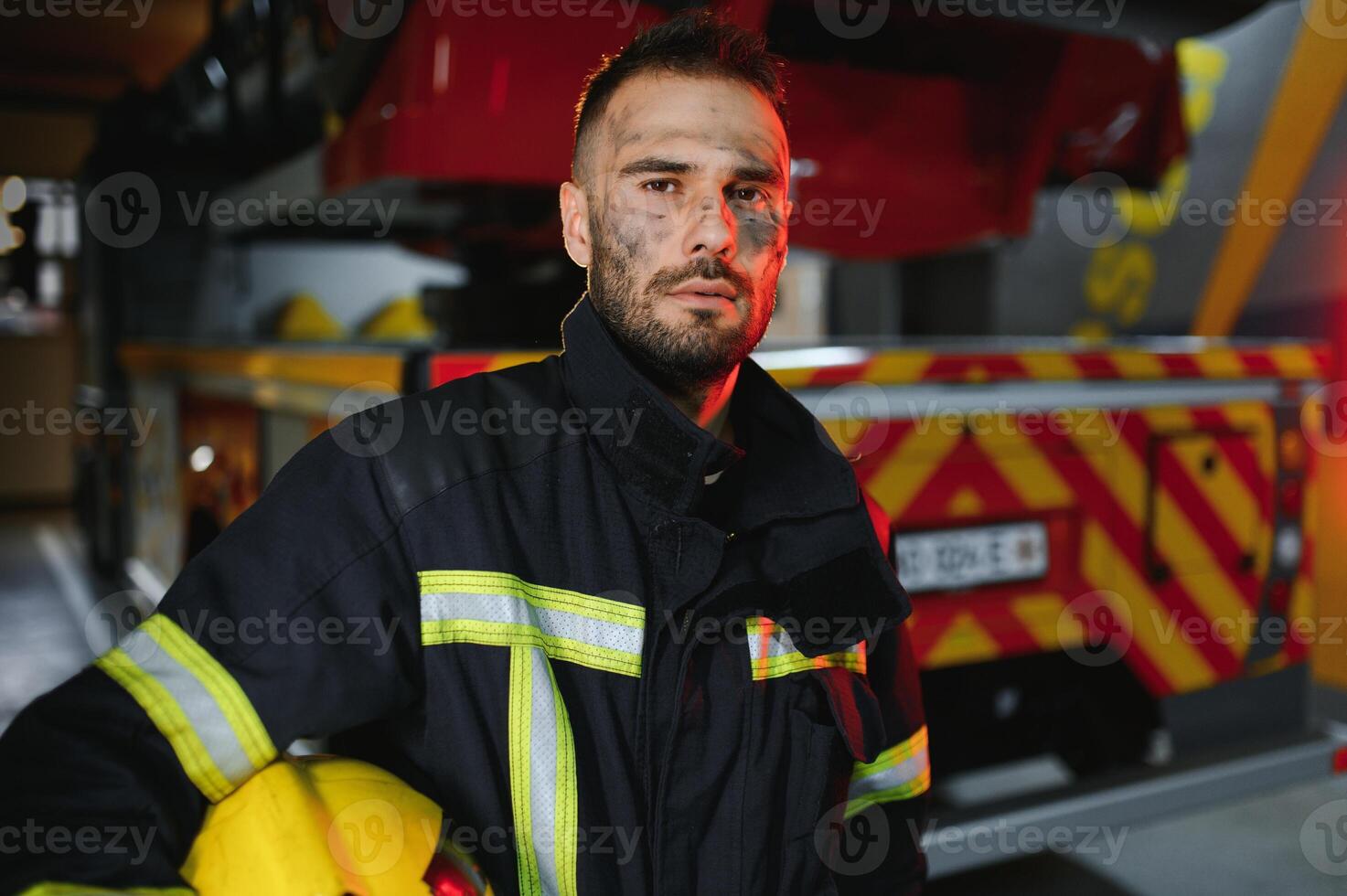 Firefighter portrait on duty. fireman with helmet near fire engine photo