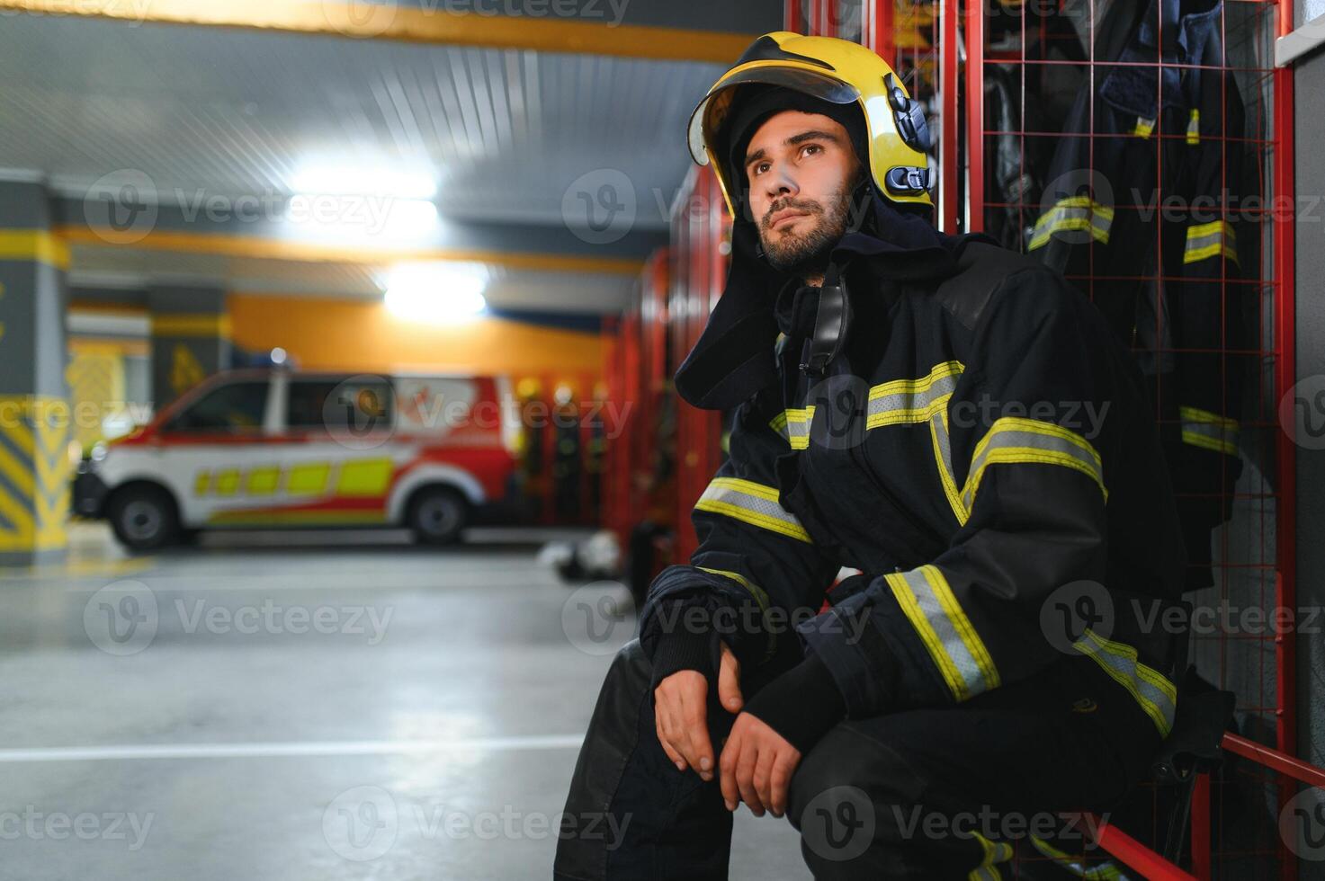Fireman wearing protective uniform standing in fire department at fire station photo