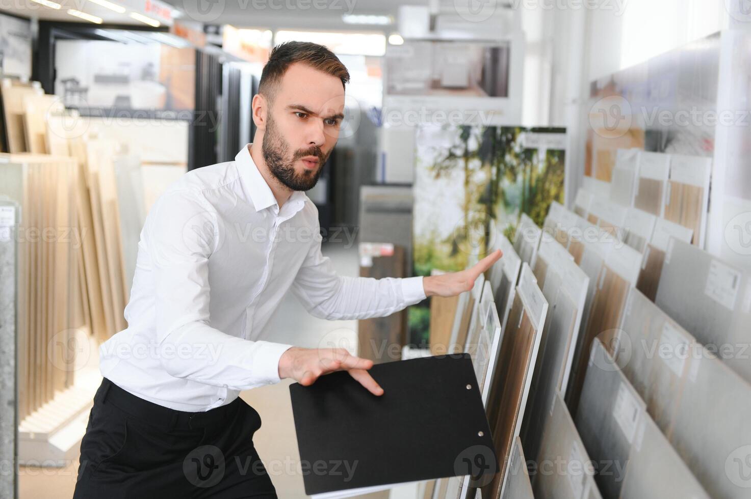 Portrait of a ceramic tile seller. The seller stands against the background of a large assortment of tiles photo