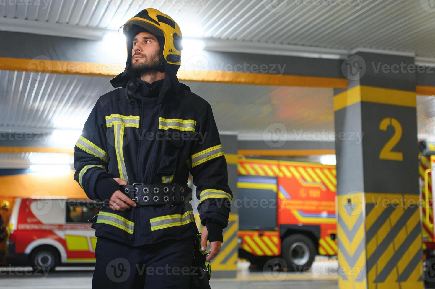 Firefighters man in a protective suit near fire truck. Protection, rescue from danger. Fire station photo