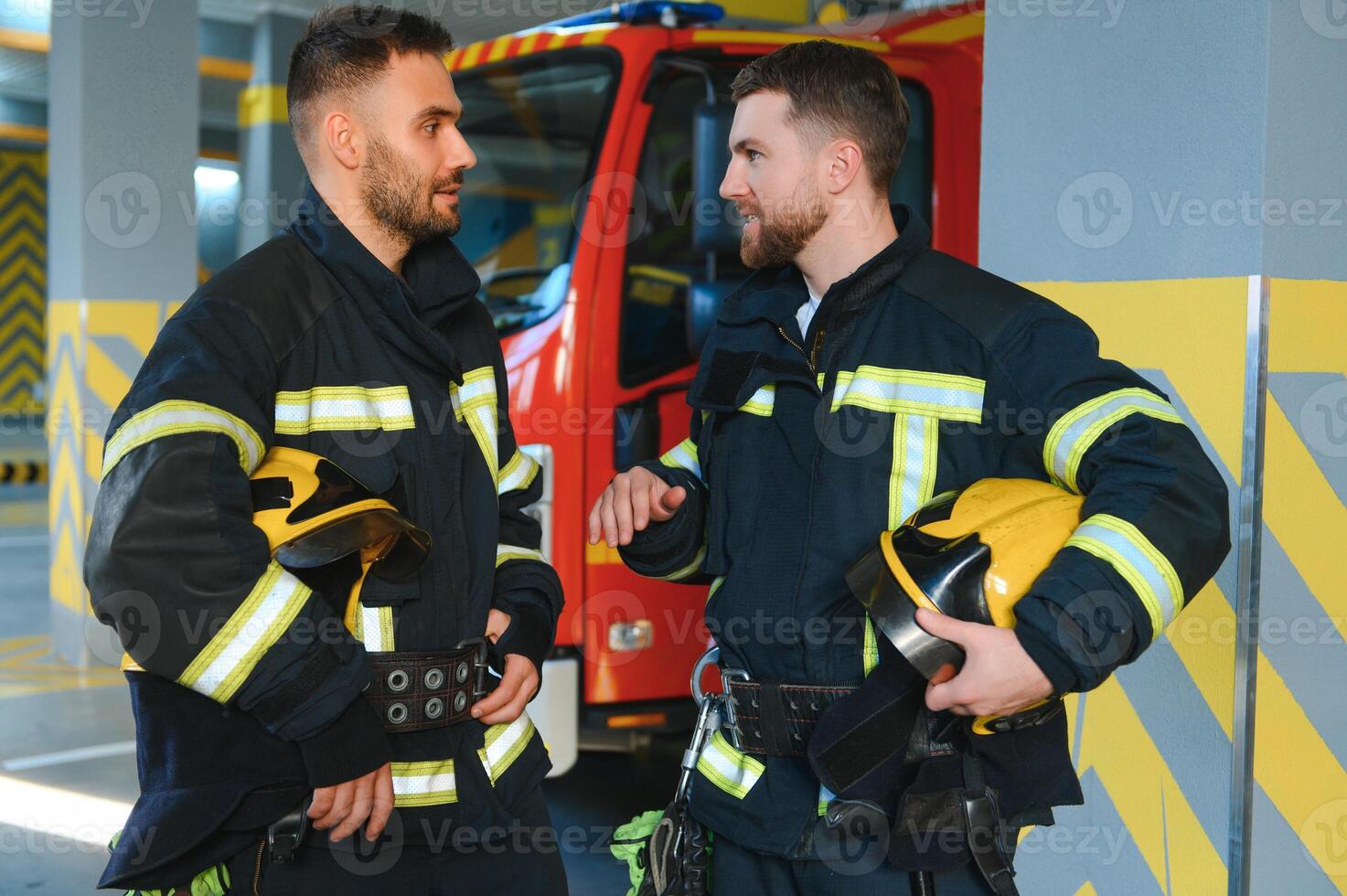 Group of firefighters at the emergency vehicle in the fire station photo