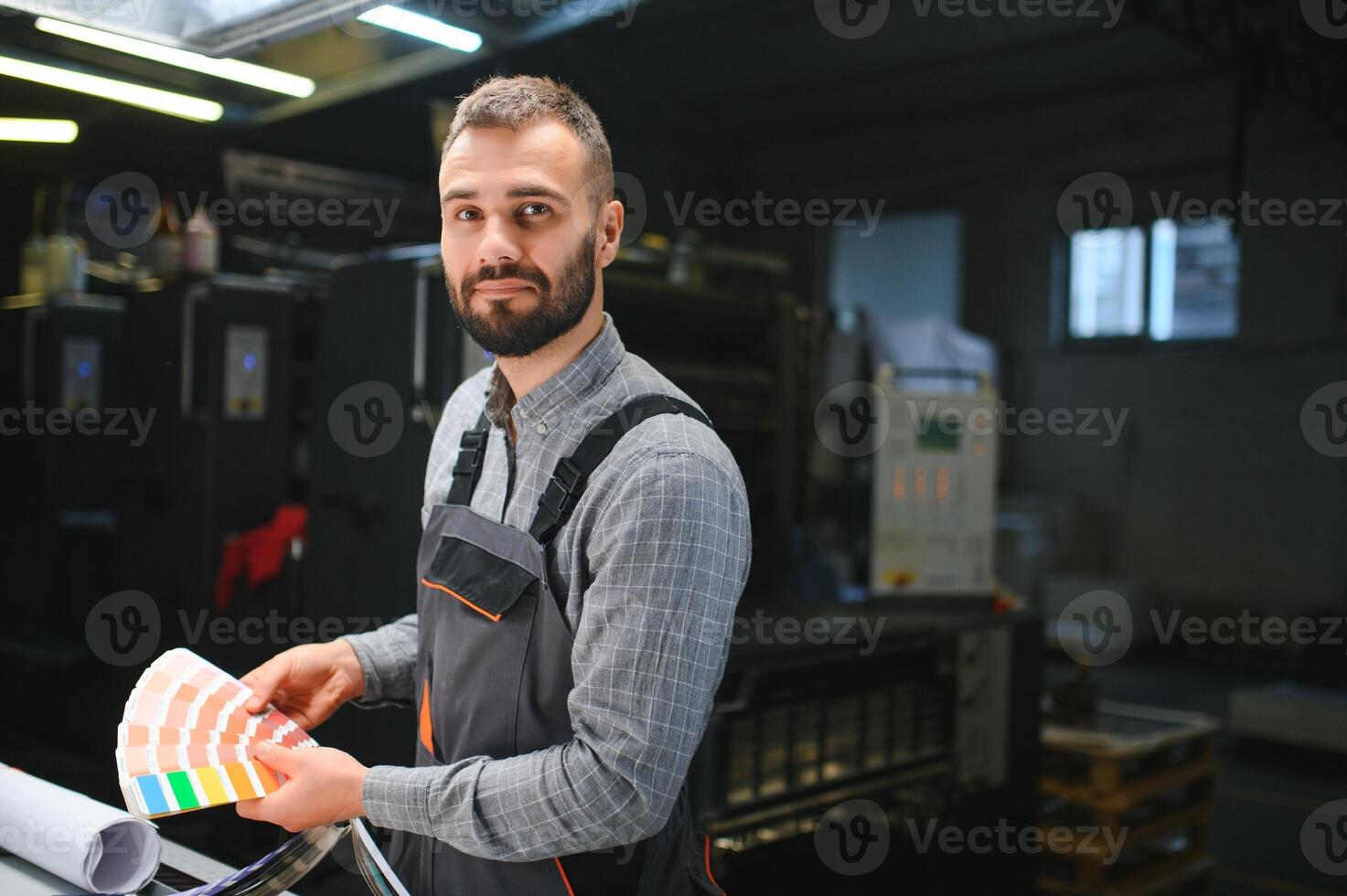 Print house worker controlling printing process quality and checking colors with magnifying glass photo