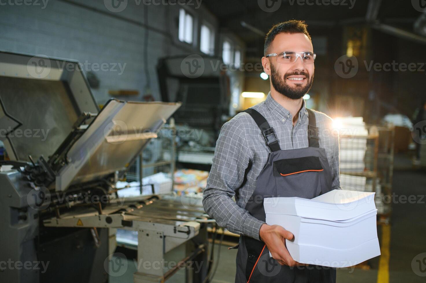 Man working in printing house with paper and paints photo