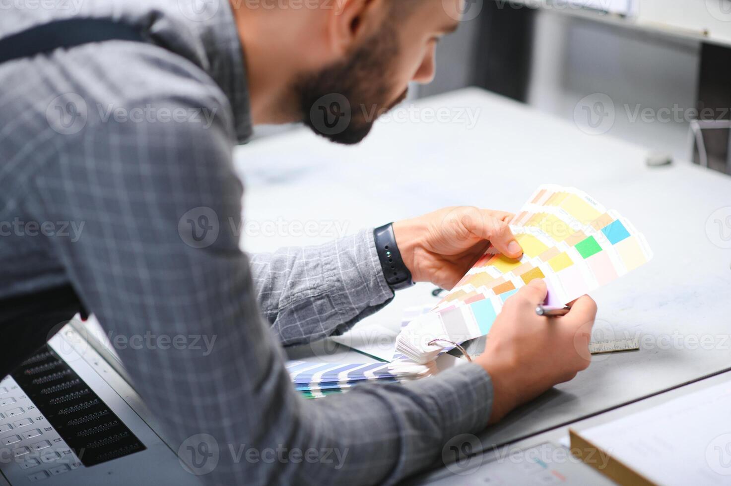 Print house worker controlling printing process quality and checking colors with magnifying glass photo