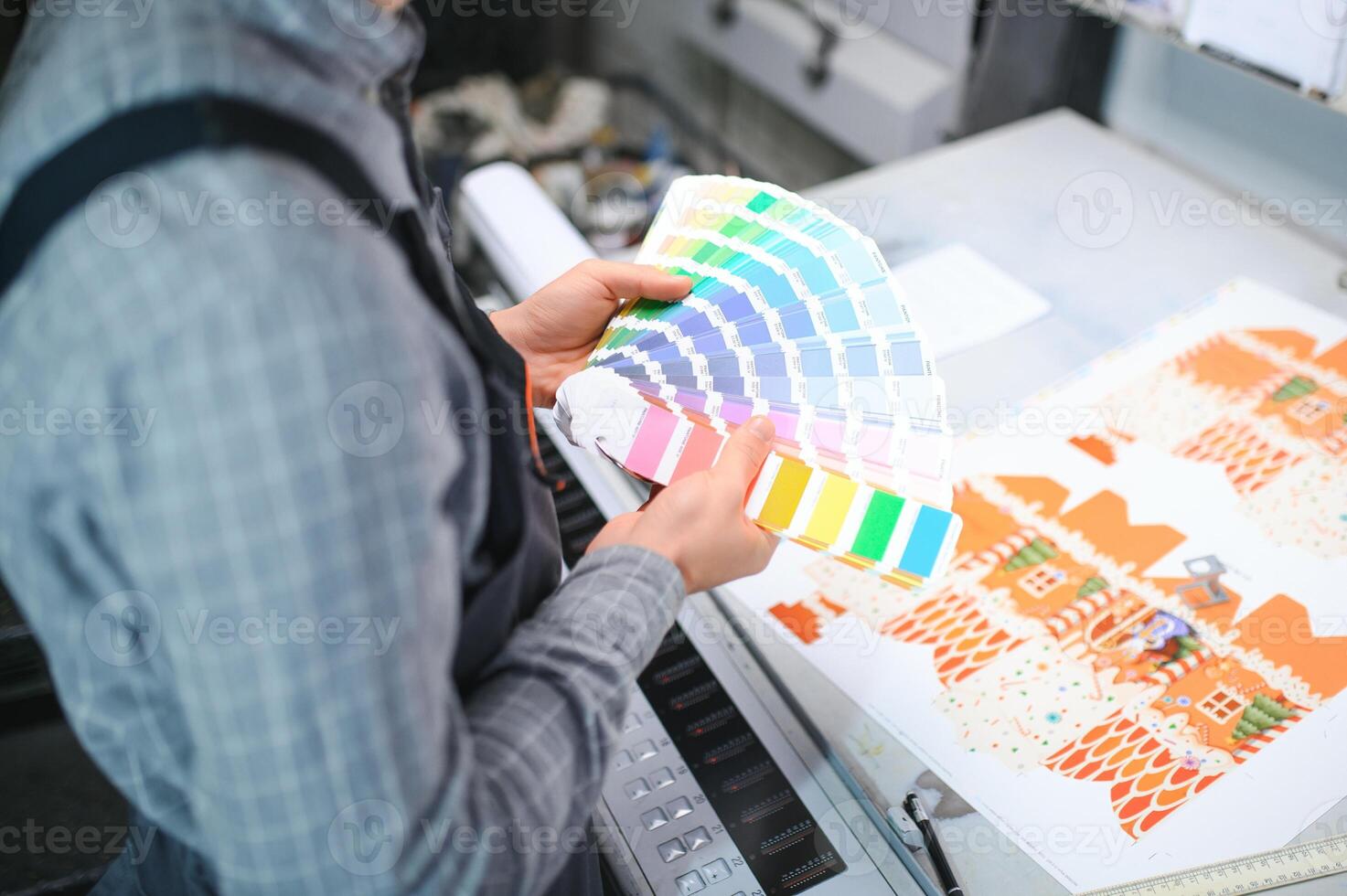 Print house worker controlling printing process quality and checking colors with magnifying glass photo