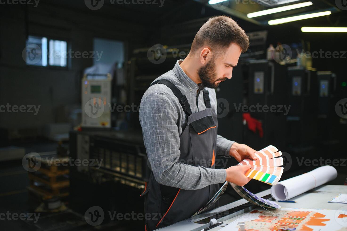 Print house worker controlling printing process quality and checking colors with magnifying glass photo