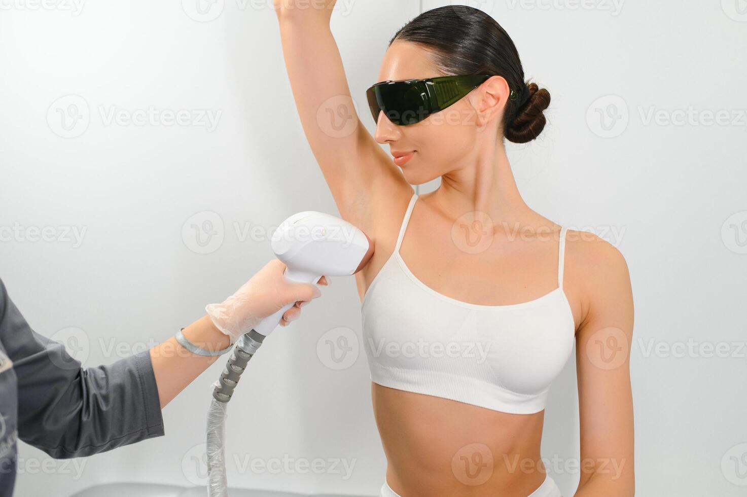 Laser cosmetology Armpit hair removal. Beautiful smiling woman client having procedure photo