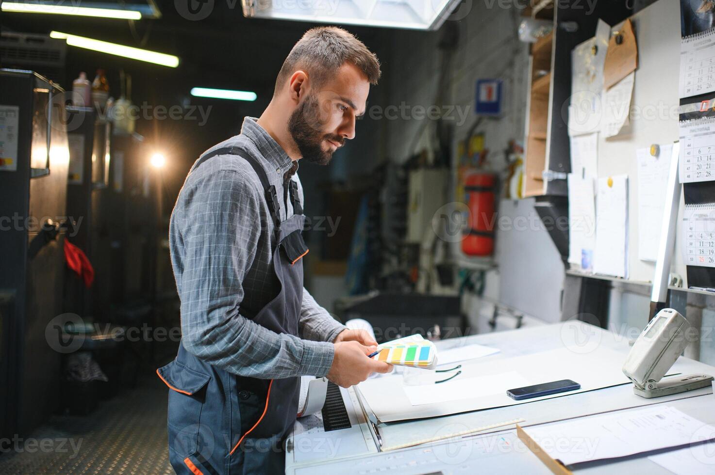 Print house worker controlling printing process quality and checking colors with magnifying glass photo