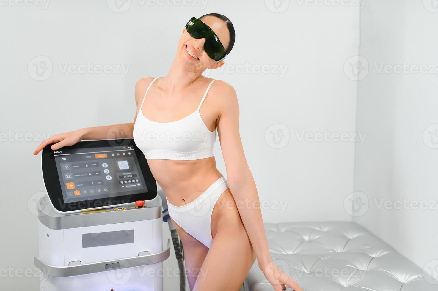 Young beautiful woman with laser hair removal machine in cosmetology cabinet photo